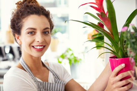 Joyful smile. Portrait of a happy nice florist smiling to you while holding a plantの写真素材