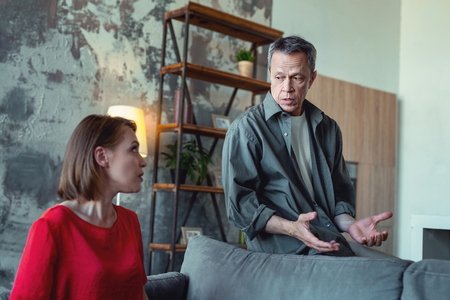 Piece of advice. Caring concerned man coming to his experienced wife for piece of advice while sitting in living roomの写真素材