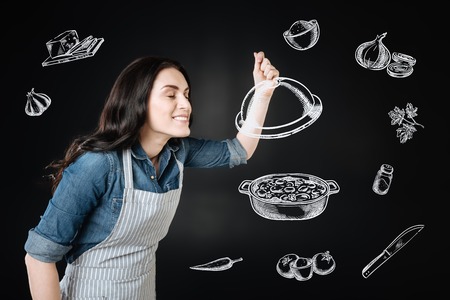 Tasty smell. Professional experienced cook being in the kitchen and standing with her eyes closed while smelling a delicious dishの写真素材