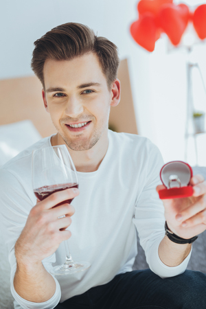 Will you marry me. Delighted nice man holding a glass of wine and making a proposal to his girlfriendの写真素材