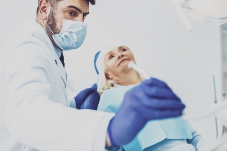 Try to relax. Handsome dentist stretching his arm while going to support his patientの写真素材