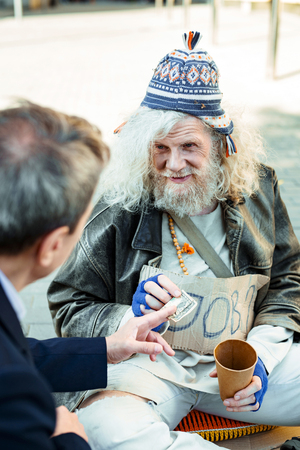 Hippy man. Unemployed elderly hippy man feeling lost and unhappy while begging for helpの写真素材