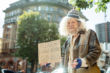 Some support. Homeless man wearing old tattered blue gloves looking for some support standing in the...