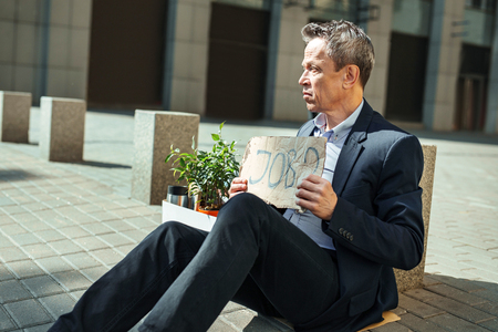 Feeling puzzled. Wrinkled elderly man wearing black suit searching new job place while feeling puzzled after being firedの写真素材
