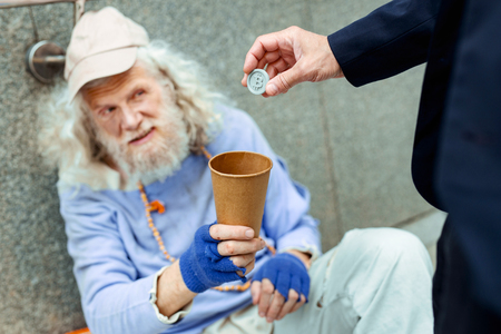 Sympathetic man. Sympathetic kind-hearted businessman providing homeless man with token for undergroundの写真素材