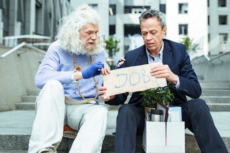 Sign for job. Hippy street man feeling very helpful while giving sign for searching job to fired man