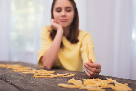 French fries. Selective focus of delicious French fries holder by attractive female hands and teen girl looking downの写真素材