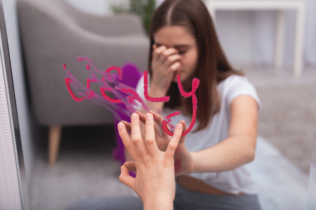 Teen age. Selective focus of pink inscription ugly on mirror and teen female hand washing itの写真素材