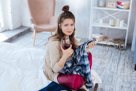 Divorce case. Young dark-haired woman drinking glass of red wine after divorce case in courtの写真素材