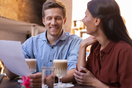 Old friend. Blonde-haired smiling man talking with his old friend while sitting in the restaurant drinking latteの写真素材