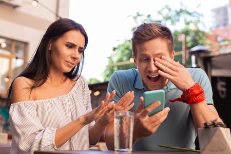 Modern man. Modern man laughing out loud while watching old photos sitting near his stylish beautiful girlfriendの写真素材