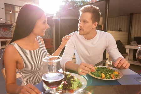 Good-looking man. Good-looking blonde-haired man feeling rested and relaxed while eating meat with his girlfriendの写真素材