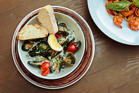 Mussels with tomatoes. Selective focus of nice delicious mussels with little cherry tomatoes and savory basilの写真素材