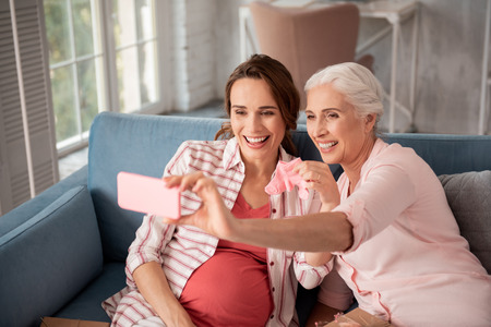 Memorable photo. Aged woman feeling really memorable while making photo with her expecting nieceの写真素材
