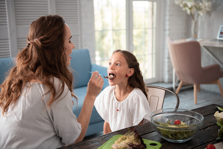 Cute girl. Cute pleasant girl wearing white blouse feeling relaxed while eating chocolate spread from spoonの写真素材