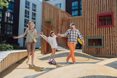 Joyful nice parent holding her daughters hand while having a walk togetherの写真素材