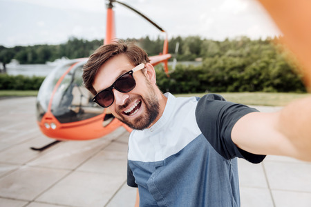 Attractive energetic man wearing sunglasses and waiting near helicopterの写真素材