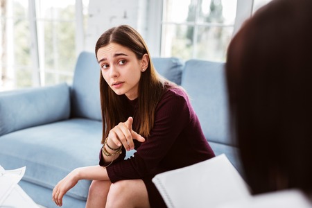 Young thoughtful woman feeling confident and interested while looking at her psychologist and taking...