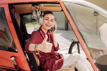 Low angle of exuberant attractive woman putting on headphones and showing thumb