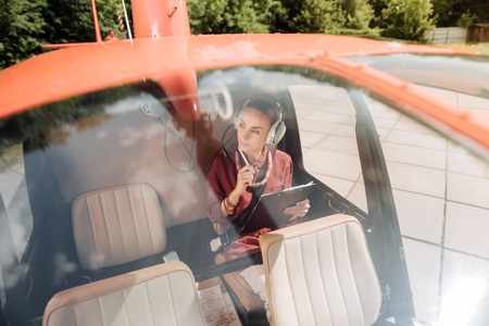 Reflective earnest woman sitting in helicopter and holding penの写真素材