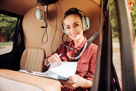 Jolly cheerful woman sitting in helicopter and carrying papersの写真素材
