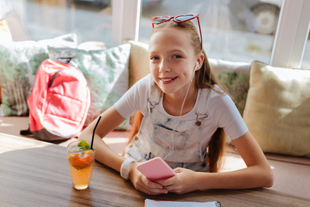 Beautiful beaming girl wearing stylish clothes relaxing while listening to musicの写真素材