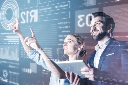 Cheerful emotional skilled programmers smiling while standing in front of the screen and working at the new programの写真素材