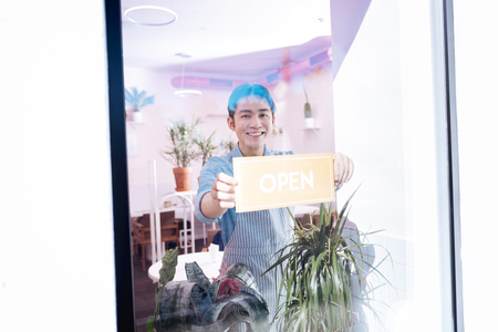 Beaming pleasant barista opening little coffee room very early in the morning