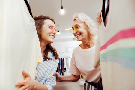 Caring stylish daughter feeling really excited while choosing new outfit for her motherの写真素材