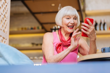 Happy joyful woman laughing while using her smartphone