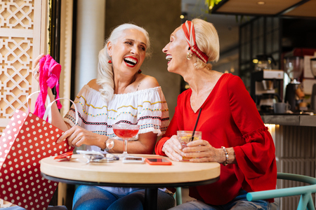 Happy nice women laughing to each other while sitting in the cafeの写真素材