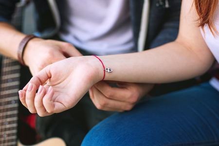 Symbol of love. Close up of a red bracelet being on the hand of a beautiful young woman