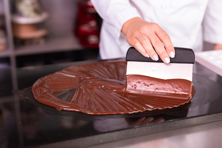 Chocolate confectionary. Skillful experienced chocolatier making white jacket cooking chocolate confectionaryの写真素材