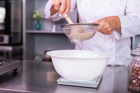 Bolting flour. Busy professional confectioner bolting flour while cooking sweet pie for her clientsの写真素材