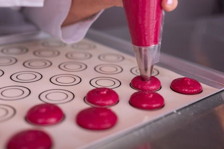 Parchment paper. Famous female chef forming little pink macaroons on cookery parchment paperの写真素材