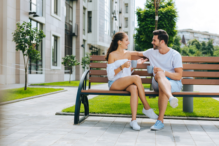 Nice happy people sitting together on the bench while having their first dateの写真素材
