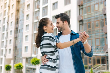 Joyful handsome man looking at his girlfriend while dancing with her