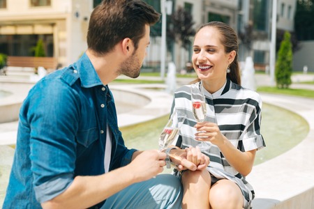 Delighted nice couple sitting together while enjoying their champagneの写真素材