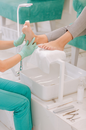 Pedicure equipment. Professional chiropodist wearing gloves using pedicure equipment enjoying the process of workの写真素材