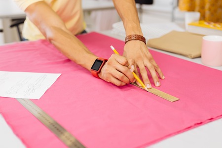 Ruler and pencil. Hands of the young man holding a ruler and a pencil and pressing them to pink...
