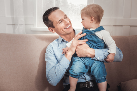 Joyful positive man smiling to his baby while feeling happyの写真素材