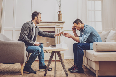 Negative delighted male person bowing head while sitting in semi position, being deep in thoughtsの写真素材
