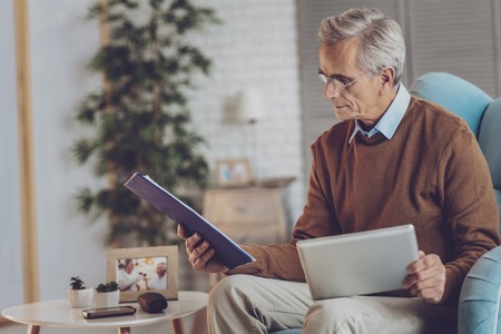 Serious old man turning head while doing his workの写真素材