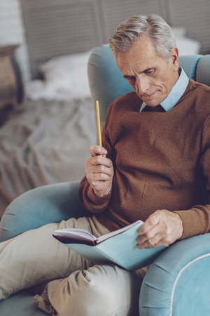 Concentrated old man sitting on his armchair while preparing for presentationの写真素材