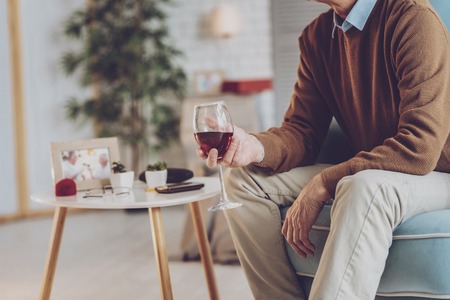 Relaxed man sitting on the armchair while enjoying alcohol drinkの写真素材