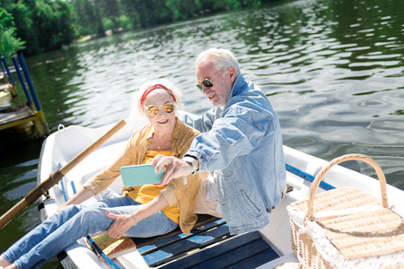 Denim jacket. Aged bearded man wearing denim jacket making memorable selfie with his appealing smiling wifeの写真素材