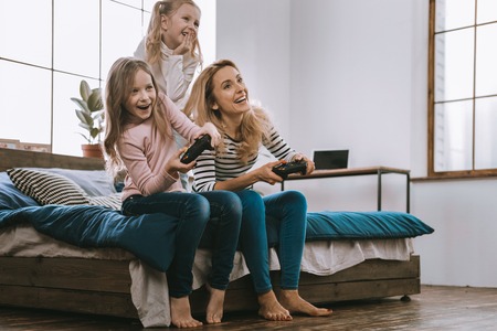 Favourite entertainment. Joyful nice family sitting together while playing video gamesの写真素材