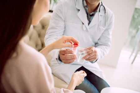 Vitamins for pregnant. Close up of medical pills in the bottle being take by a nice pleasant pregnant womanの写真素材