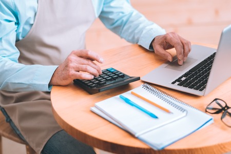 Daily calculation. Professional businessman using calculator while counting incomes of his business