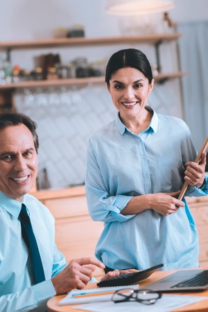 Business with pleasure. Attractive woman keeping smile on face and holding folder with documentsの写真素材